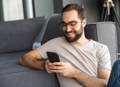 Homem mexendo no celular e sorrindo